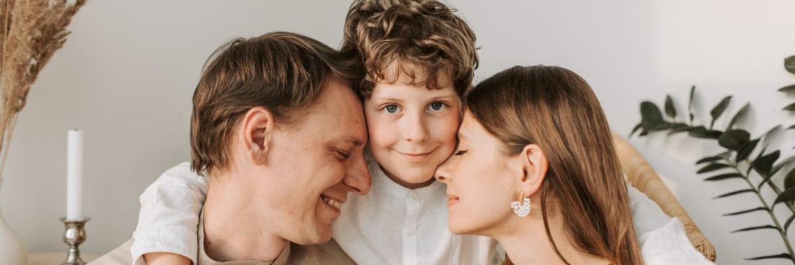 A joyful family moment with parents and their son embracing indoors.